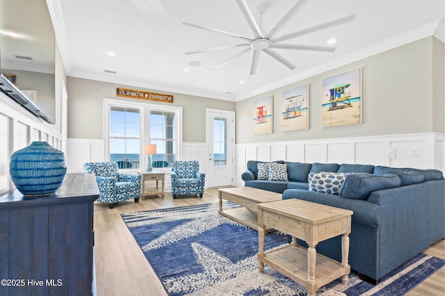 living room featuring ceiling fan, ornamental molding, and wood-type flooring