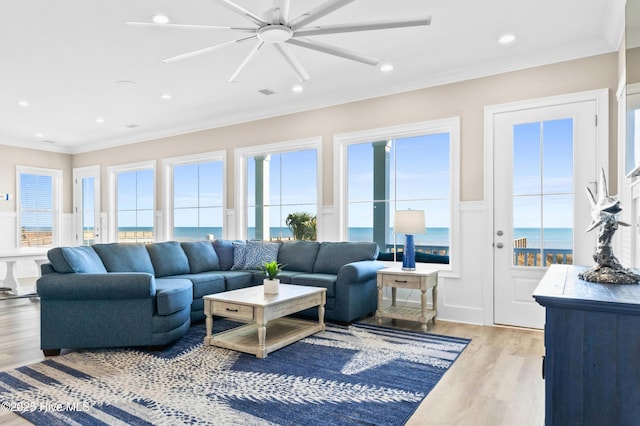 sunroom featuring ceiling fan and a water view