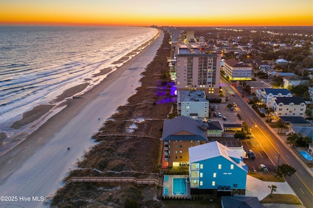 aerial view at dusk with a beach view and a water view