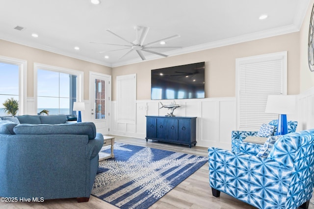 living room with light hardwood / wood-style floors, a wealth of natural light, crown molding, and ceiling fan