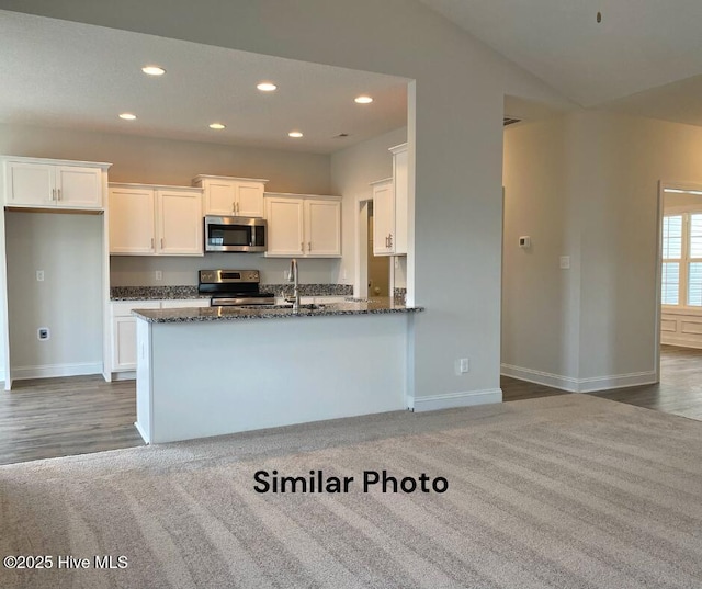 kitchen featuring white cabinetry, dark colored carpet, dark stone countertops, vaulted ceiling, and appliances with stainless steel finishes