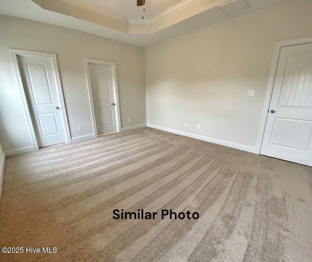 unfurnished room with a tray ceiling, crown molding, carpet, and ceiling fan