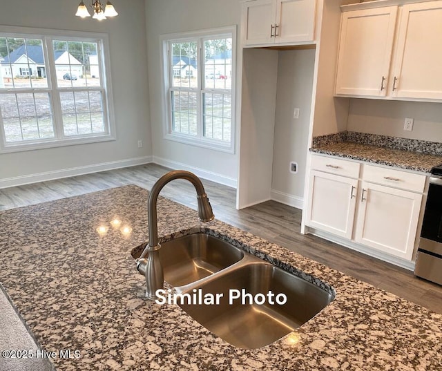 kitchen with dark stone counters, white cabinets, sink, dark hardwood / wood-style floors, and a chandelier