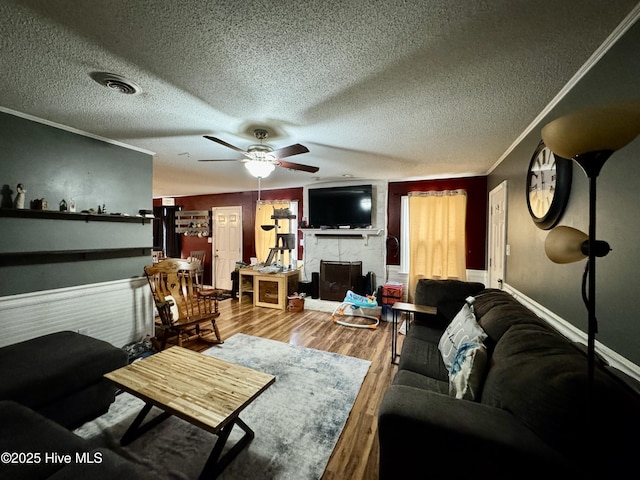 living room with hardwood / wood-style flooring, ceiling fan, ornamental molding, and a textured ceiling