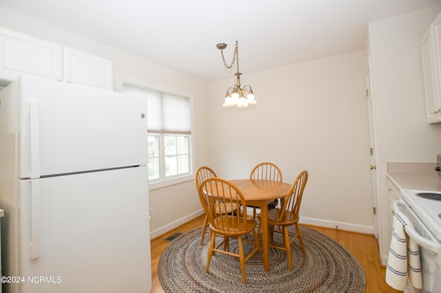 dining area with a notable chandelier and light hardwood / wood-style flooring