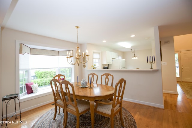 dining space featuring light wood-type flooring and an inviting chandelier