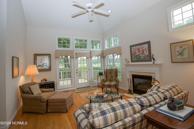 living room featuring a high ceiling, a premium fireplace, light hardwood / wood-style floors, and a healthy amount of sunlight