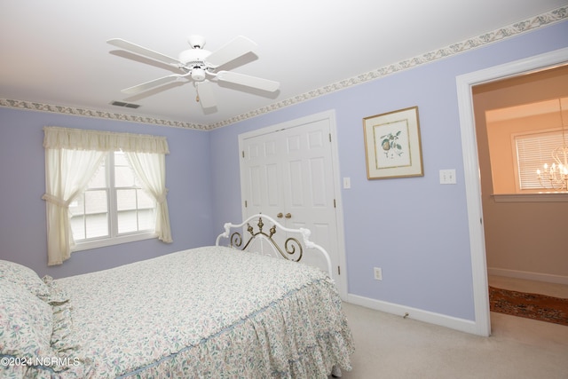 carpeted bedroom featuring ceiling fan with notable chandelier and a closet