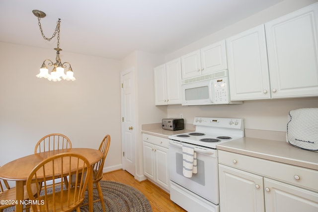 kitchen featuring white appliances, hanging light fixtures, white cabinets, and an inviting chandelier