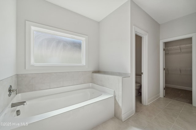 bathroom featuring a tub, tile patterned floors, and toilet