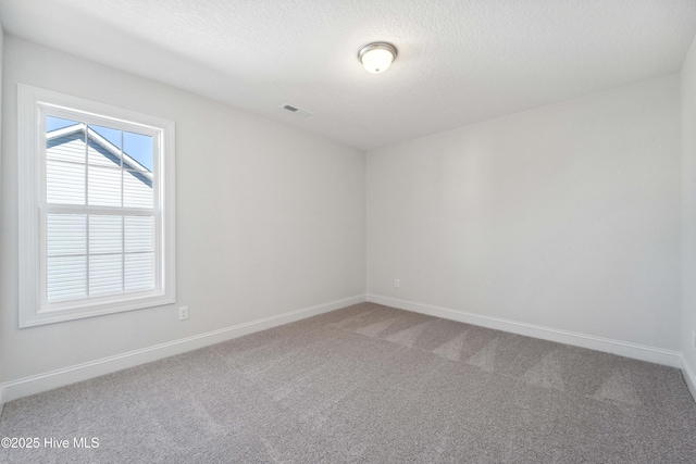 carpeted empty room featuring a textured ceiling