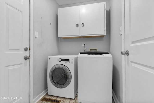 clothes washing area featuring washer and dryer and cabinets