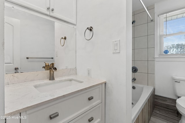 full bathroom featuring toilet, tiled shower / bath, and vanity