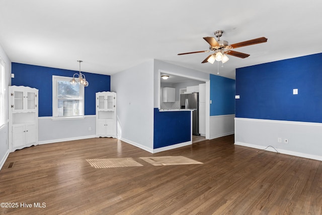 unfurnished living room featuring ceiling fan with notable chandelier and dark hardwood / wood-style floors