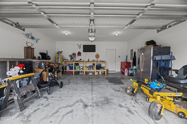 garage with stainless steel fridge, a workshop area, and a garage door opener