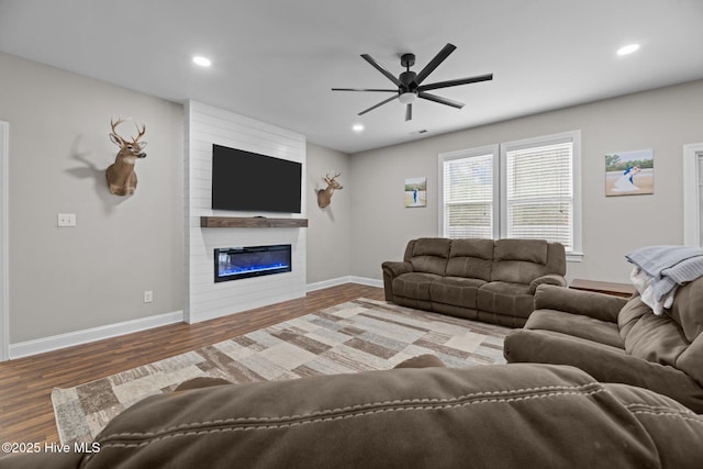 living room with a large fireplace, hardwood / wood-style flooring, and ceiling fan