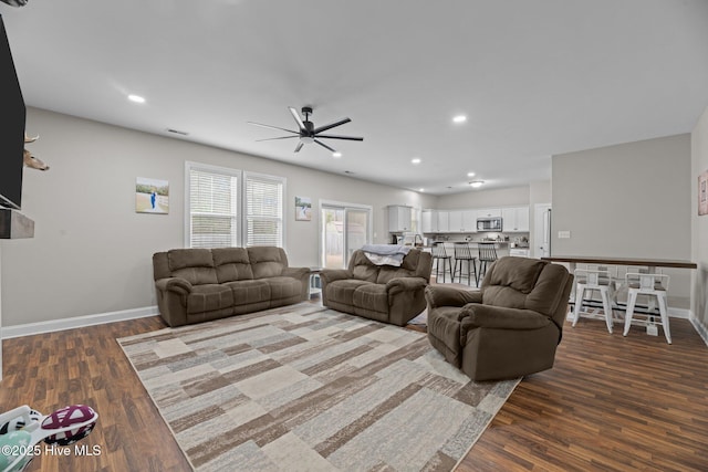 living room with ceiling fan and dark wood-type flooring