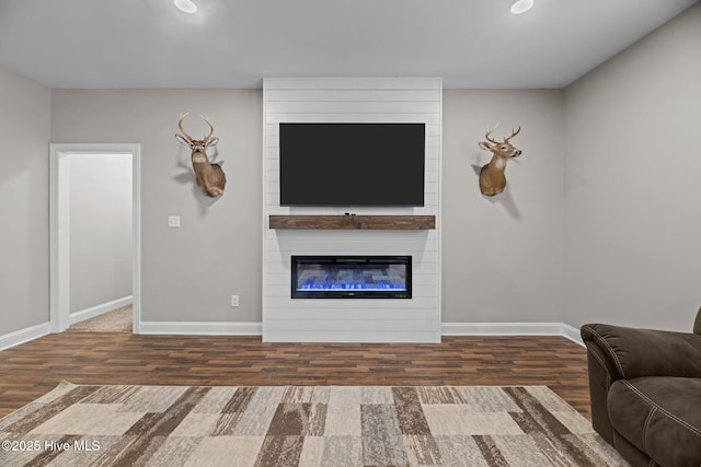 living room with a large fireplace and dark wood-type flooring