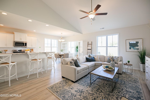 living room featuring ceiling fan with notable chandelier, light hardwood / wood-style flooring, and a healthy amount of sunlight