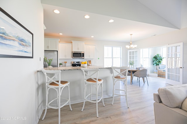 kitchen with a kitchen breakfast bar, tasteful backsplash, white cabinets, and appliances with stainless steel finishes