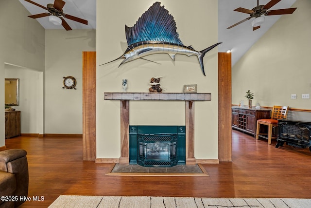 living room with hardwood / wood-style floors, high vaulted ceiling, ceiling fan, and a wood stove