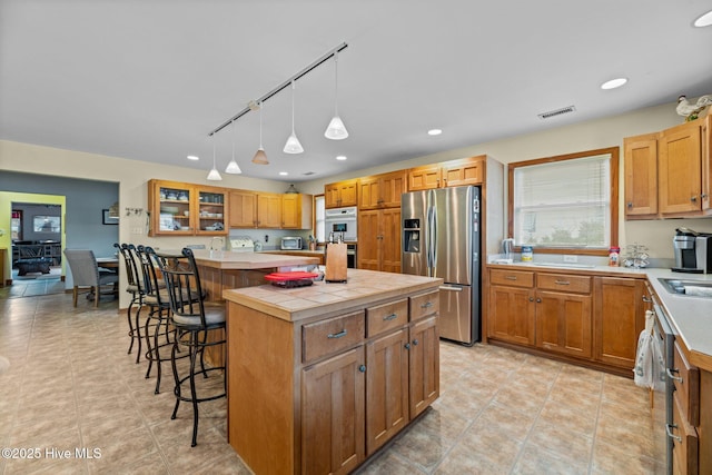 kitchen with stainless steel appliances, a kitchen island, track lighting, and a kitchen breakfast bar