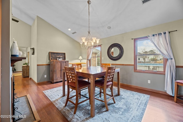 dining room with a notable chandelier, vaulted ceiling, and light hardwood / wood-style floors