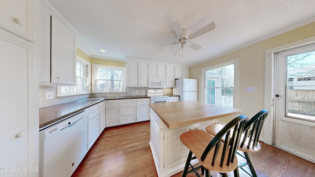 kitchen featuring hardwood / wood-style flooring, white appliances, a wealth of natural light, and white cabinets