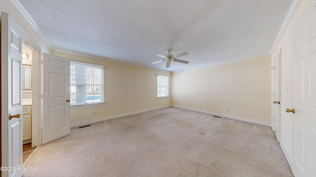 spare room featuring crown molding, light carpet, ceiling fan, and a textured ceiling