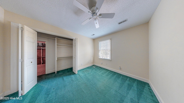 unfurnished bedroom featuring ceiling fan, a textured ceiling, dark carpet, and a closet