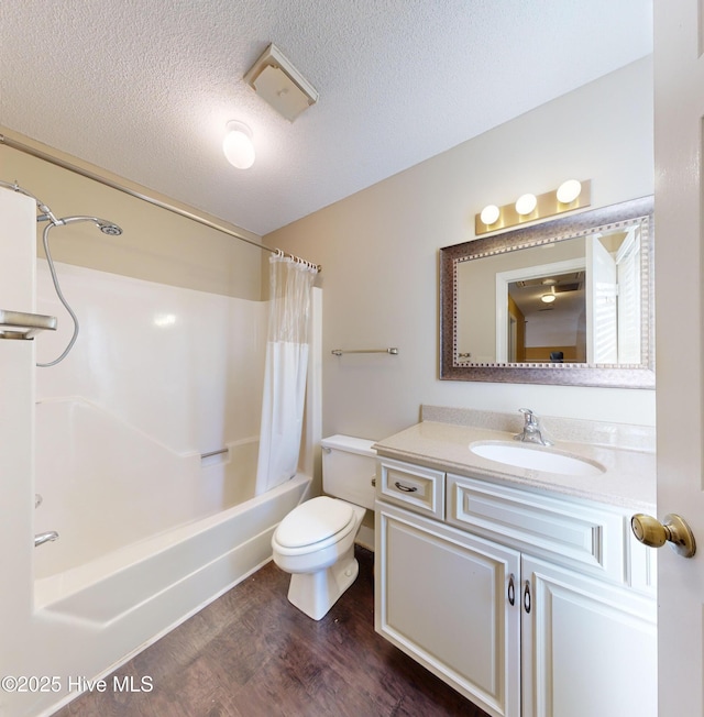 full bathroom featuring shower / tub combo with curtain, wood-type flooring, vanity, toilet, and a textured ceiling