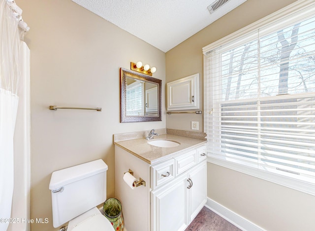 bathroom with vanity, plenty of natural light, toilet, and a textured ceiling