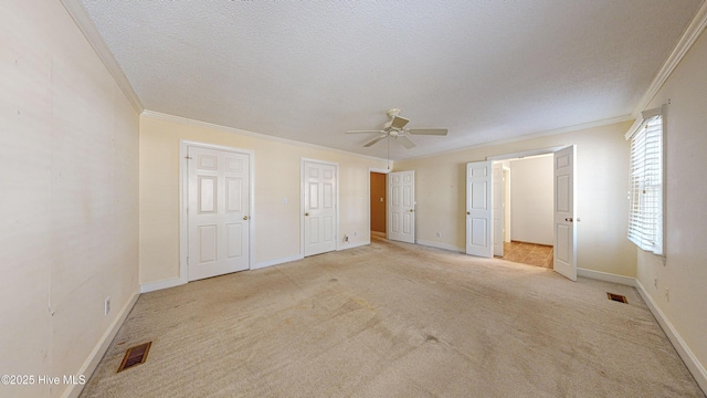 unfurnished bedroom with crown molding, light colored carpet, and a textured ceiling