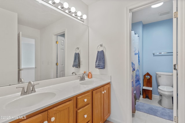 bathroom featuring visible vents, a sink, toilet, and double vanity