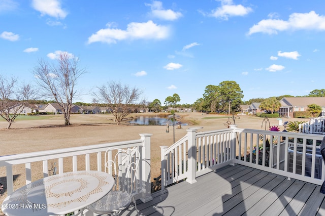 wooden deck with a residential view, outdoor dining area, and a water view