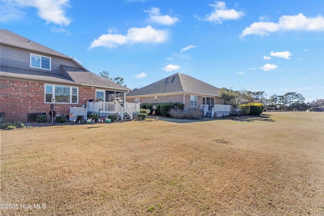 rear view of house featuring a yard and brick siding