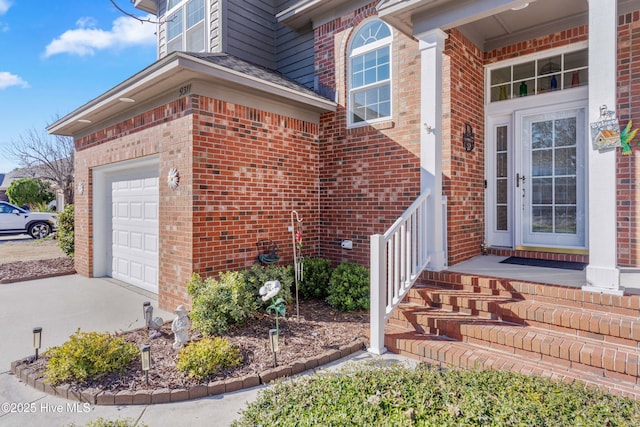 property entrance with concrete driveway, brick siding, and an attached garage