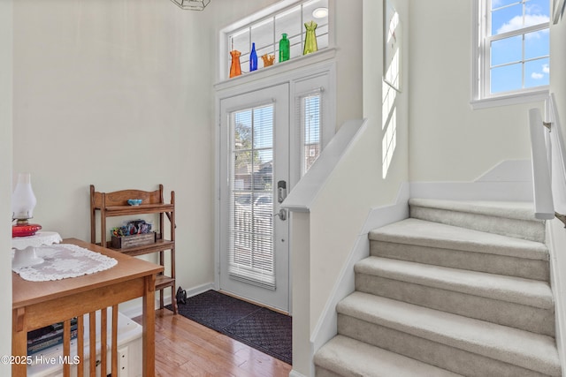 entryway with a healthy amount of sunlight, baseboards, stairway, and wood finished floors