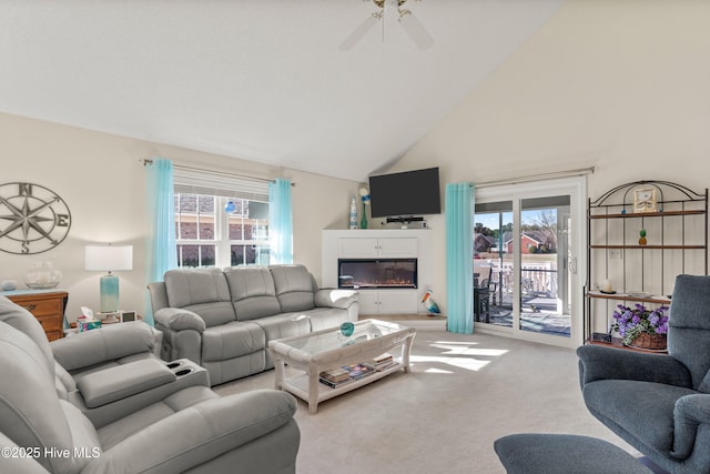 carpeted living room featuring high vaulted ceiling, a glass covered fireplace, and ceiling fan