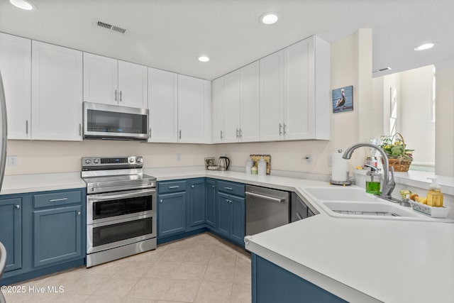 kitchen with blue cabinets, stainless steel appliances, a sink, white cabinetry, and visible vents