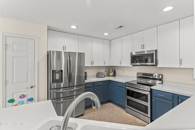 kitchen with light tile patterned floors, light countertops, appliances with stainless steel finishes, white cabinetry, and blue cabinets