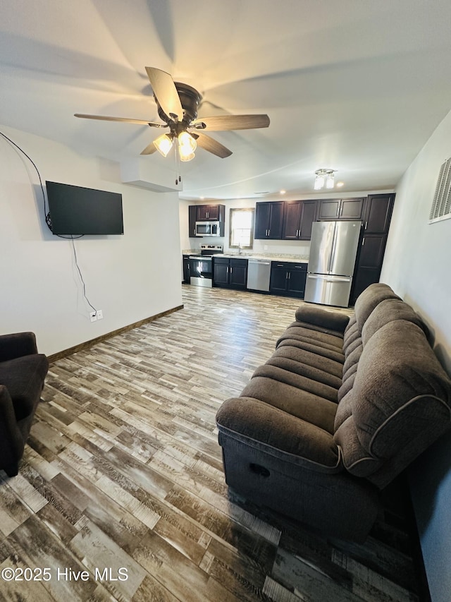 living room with light wood-type flooring, ceiling fan, and sink