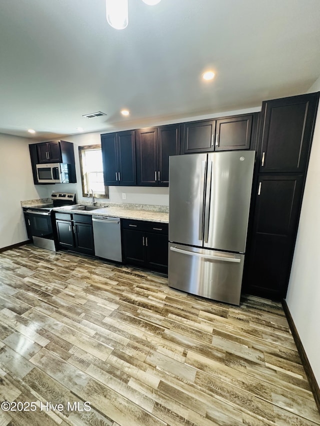 kitchen with sink, appliances with stainless steel finishes, and light hardwood / wood-style flooring