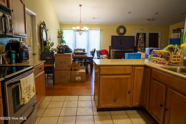 kitchen with sink, light tile patterned floors, a chandelier, pendant lighting, and appliances with stainless steel finishes