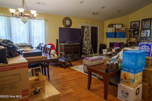 living room with a notable chandelier, vaulted ceiling, and hardwood / wood-style flooring