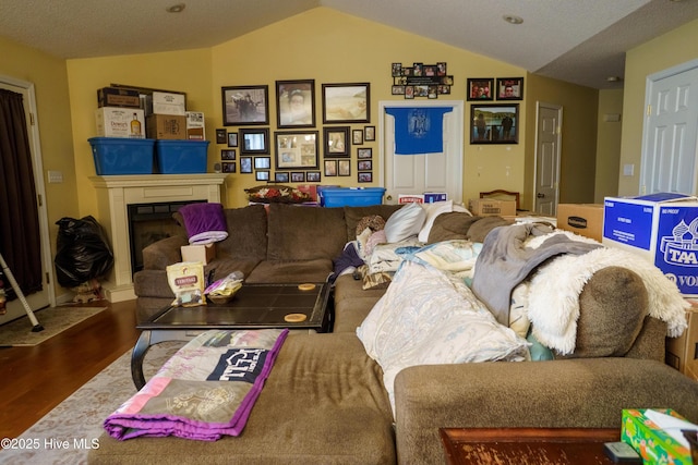 living room with a textured ceiling, vaulted ceiling, and hardwood / wood-style flooring