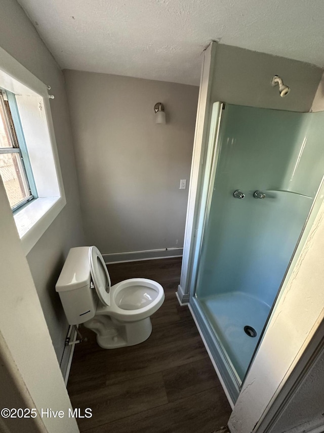 bathroom featuring hardwood / wood-style floors, toilet, a shower with shower door, and a textured ceiling