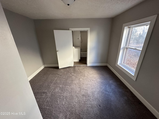 unfurnished bedroom with dark colored carpet and a textured ceiling