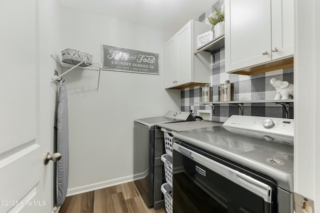 clothes washing area featuring independent washer and dryer, cabinets, and hardwood / wood-style floors