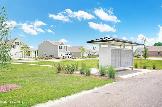 view of property's community featuring a mail area and a lawn